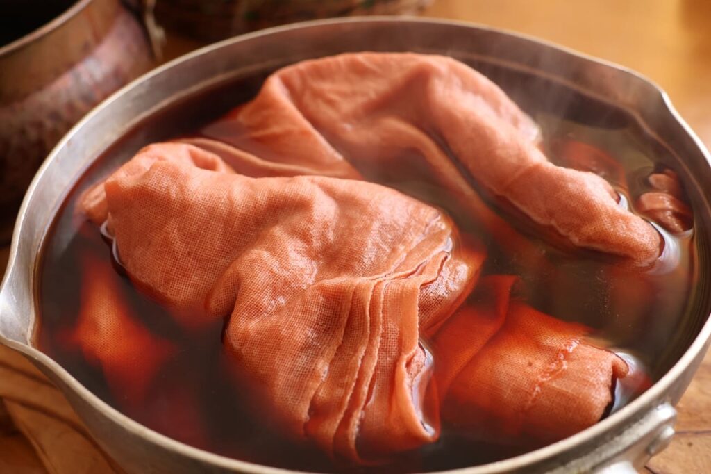 桜の染液に布を浸け込む